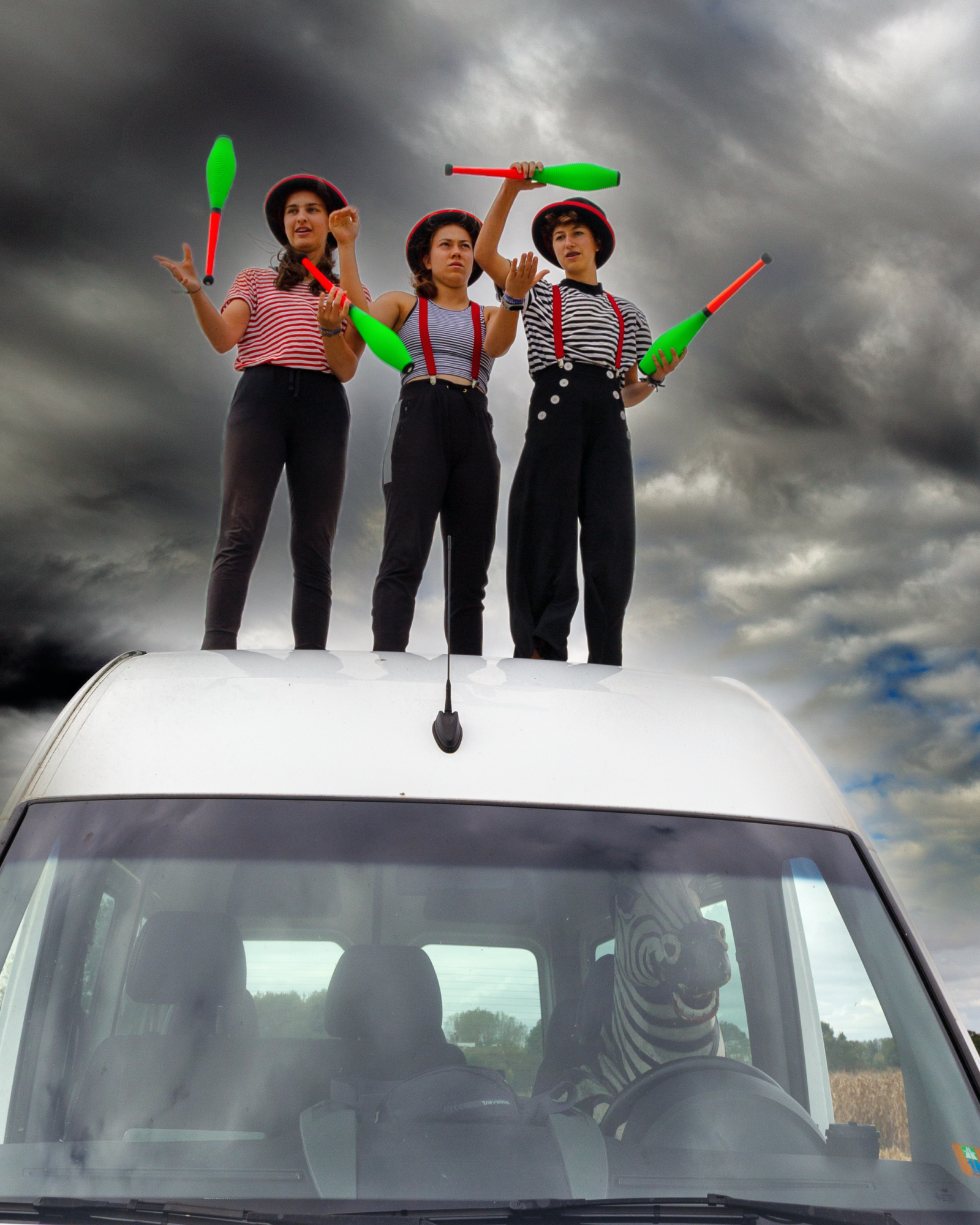 Drei Artsitinnen stehen auf dem Dach unserer Zirkusbusses und Jonglieren