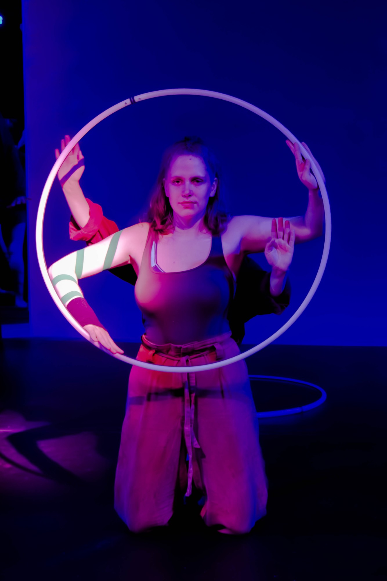 Zwei Artistinnen halten einen Hula Hoop Reifen, das Licht ist lila.