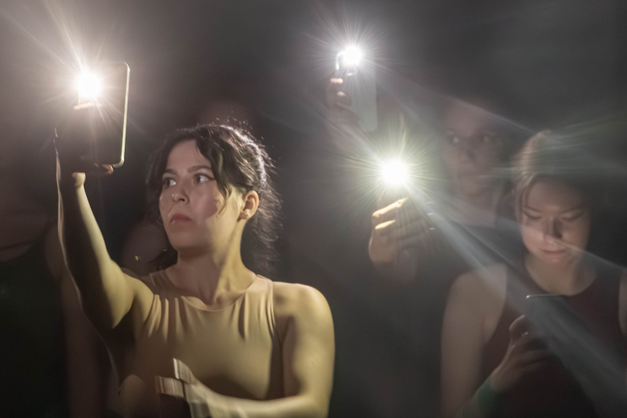 Artisten halten das Handy vor sich und leuchten mit der Handytaschenlampe richtung Publikum.